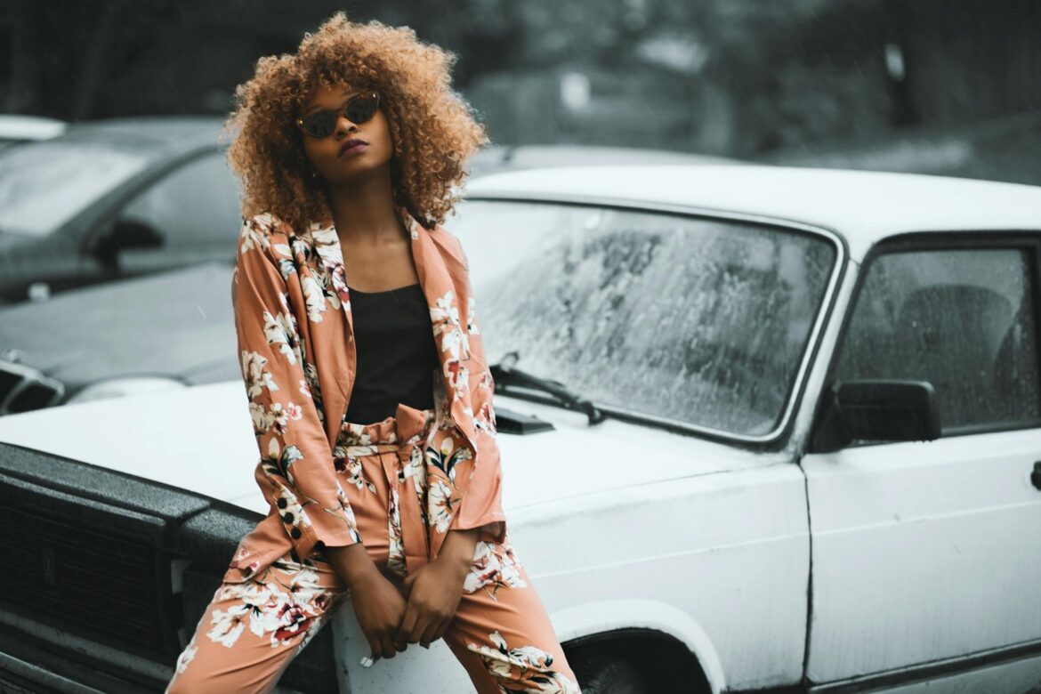 pexels-photo-923229 woman wearing brown floral print coat and pants sitting on car